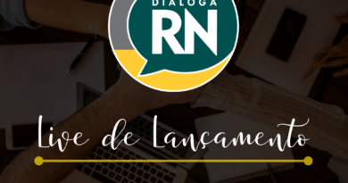 [descrição da imagem] Banner de divulgação do evento. Quadrado colorido. No plano de fundo, uma foto que apresenta a vista de cima de uma mesa de trabalho, na qual se encontram celulares, cadernos, canetas e um notebook. Cinco pessoas dão as mãos sobrepostas umas às mãos das outras no centro da imagem, num gesto que representa união e espírito de equipe. Em destaque e no centro da imagem, o logotipo do coletivo Dialoga RN. Logo abaixo, lê-se o título “Live de Lançamento”, escrito em letra manuscrita. Separado por uma linha horizontal amarela, a parte inferior da imagem traz as informações “13 de abril, 19h, @coletivodialogarn”, acompanhados de uma logo simplificada do Instagram. [fim da descrição]